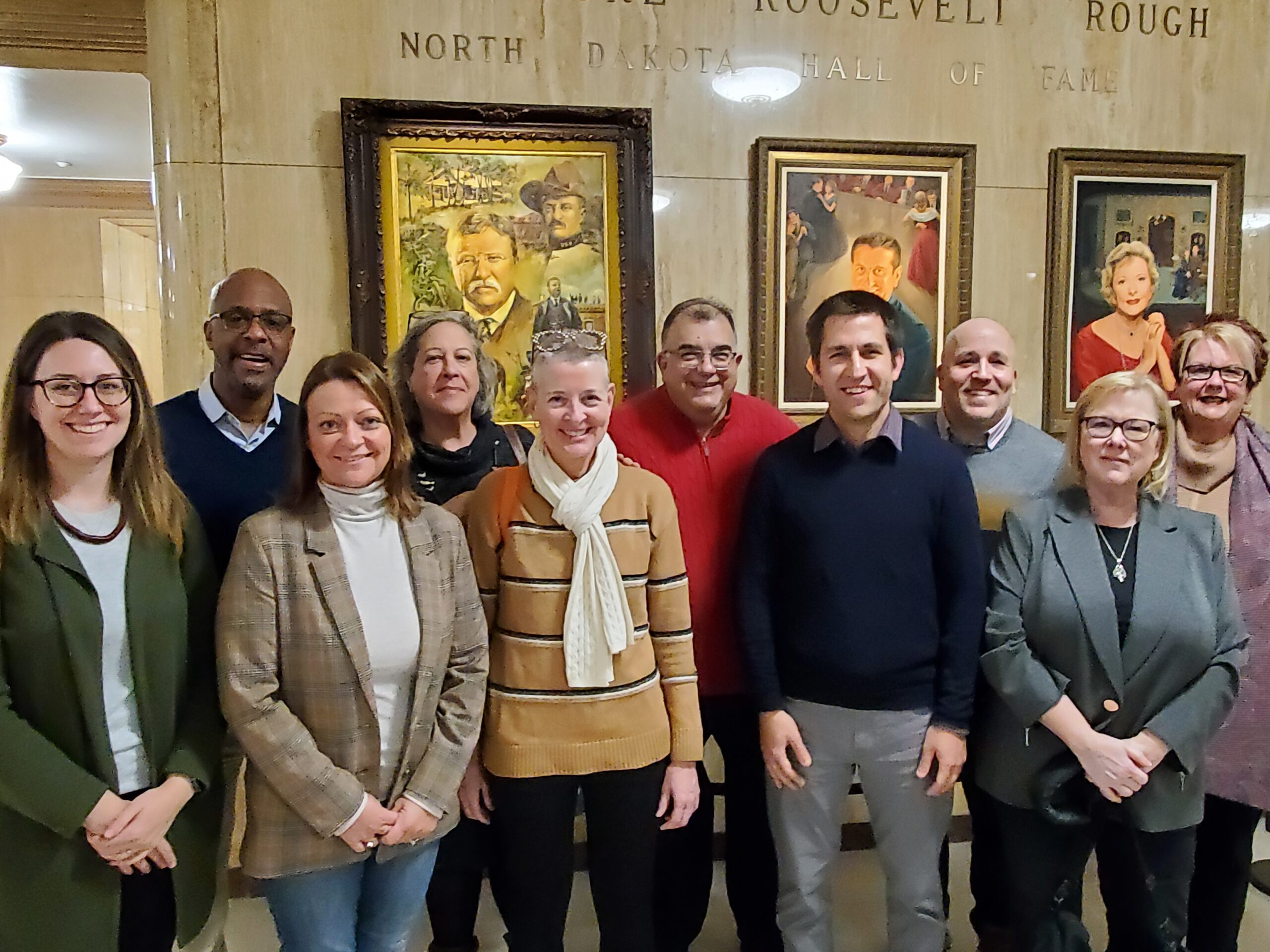 A group of eleven people in formal businessware pose for the camera.